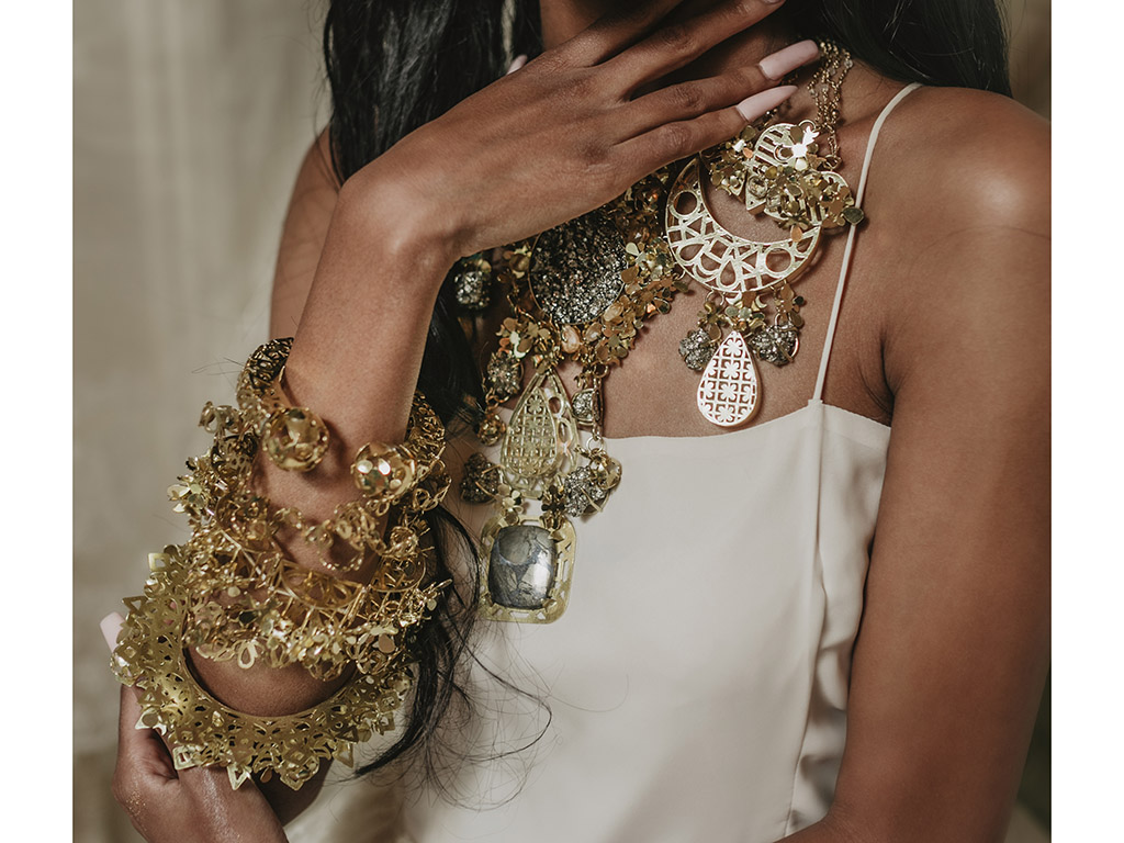 “I construct abstract elements to create jewelry in an overpowering scale that consumes the body in its shimmer to celebrate past and present, and to make future memories,” states Raijada. | Divya Raijada, A Glittering Experience, 2021, bangles, (top to bottom) Kada, hand-pierced brass; Chuddi, hand-pierced brass; Gajra, hand-pierced brass and rose-cut glass; Chuddi, hand-pierced brass; Bangdi, hand-pierced brass; model: @abbyblazee, set design: @jkchaotic, photo: @kayleighsclicks Divya Raijada, A Glittering Experience