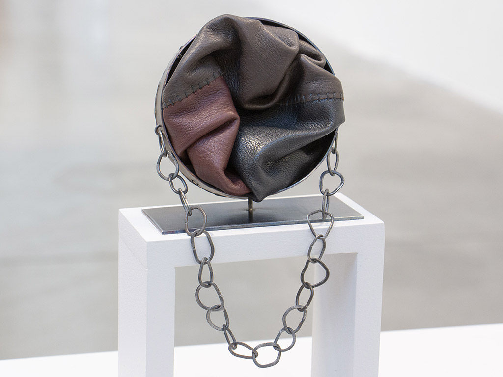From Borgelin’s artist statement: “Identity is not just about how we see and define ourselves, but among other things, it is shaped by the gazes of other people and the society we live in. In Who I Am and Who You See, my experiences of being transnational adopted becomes the starting point for my degree project, which investigates the interplay of personal and social identity and how we classify things in our environment and push them into categories, including appearance. The color of the skin leads to questions about norms, categorization, inclusion, exclusion, and the power we all have of labeling another person. This is explored through different materials and techniques and eventually transformed into brooches. These jewelry objects become conversation pieces which talk about value, power structures, and displacement, but also about care and heritage.” | Teresa Alton Borgelin, Who I Am and Who You See, 2021, brooch, leather, iron, false sinew, stainless steel, 130 x 80 mm, photo: artist Teresa Alton Borgelin, Who I Am and Who You See