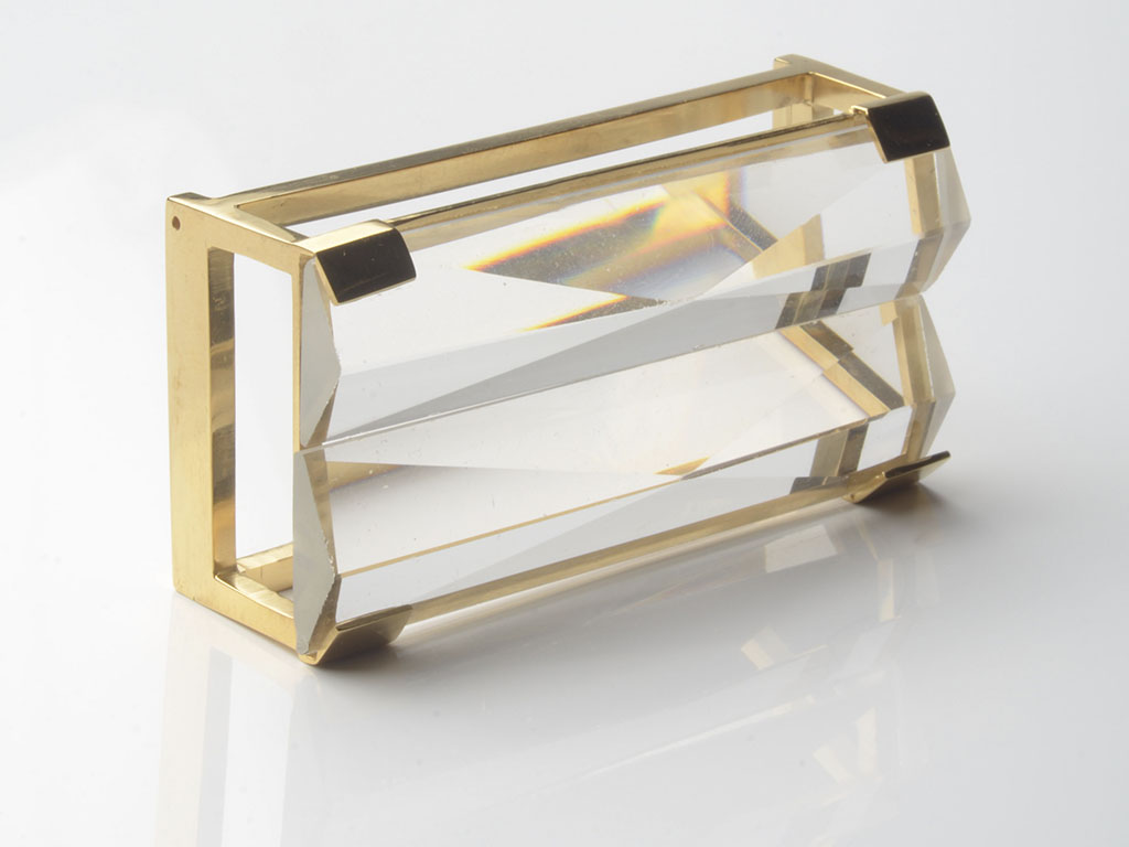 “Initially I made a virtual collection of commonly used illusions in daily life and in art, all emerging from different uses of glass,” explains Timkova. “It was amazing to learn that we are confronted daily with these phenomena. Based on this information I developed a general working methodology. More specifically, I experimented with enlarging and reducing lenses, with glass volumes, and with fused crystal of various shapes and textures to create a diversity of optical effects.” | Olha Timkova, Pendant, brass, glass, steel, 100 x 30 x 30 mm, photo: artist Work by Olha Timkova