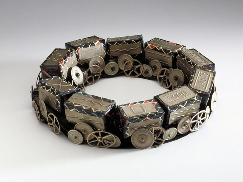 Esther Knobel, Train, 1987, necklace, tin, paint, textile, photo courtesy Françoise van den Bosch Foundation. The text reads “Ford lasts longer.” Esther Knobel, Train