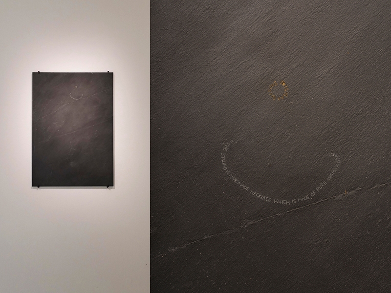 Qi Wang, Stone Poster, 2015, wall object, slate, gold, 594 x 420 x 5 mm, photo: artist. On the left side of the photo you see the entire wall piece. On the right side is a detail from the wall piece which reads, “the string is handmade necklace which is made of pure diamond and” and “this is an earring.” Qi Wang, Stone Poste