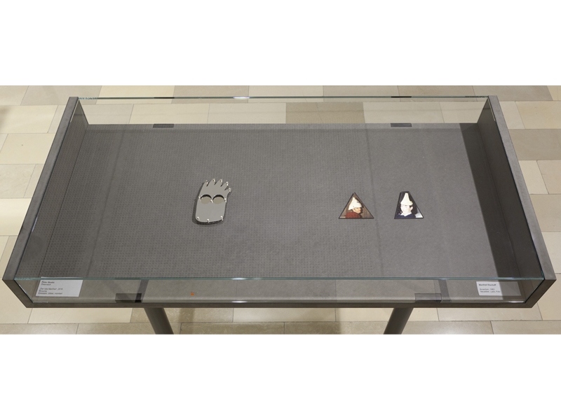 Exhibition view, Tribute to Manfred Bischoff, 2017, Left: Peter Skubic, Der Tote Manfred (The Dead Manfred), 2016, brooch, steel, silver and right: Manfred Bischoff, two brooches, 1983, silver, lacquer, Handwerkskammer München, photo: Wilfried Petzi Exhibition view, Tribute to Manfred Bischoff, 2017