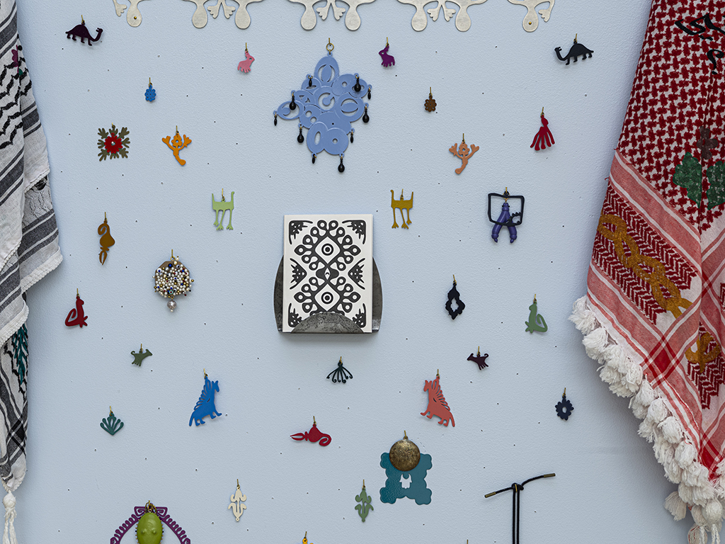 “Ornamentation is used to emphasize surfaces and add further confusion in the forms,” Almajidi continues. “Pins, pearls, and plastic components commonly function as markers adorning the surface of seemingly meaningless forms. They protrude from the manipulated surfaces of the jewelry, increasing the wearers’ awareness of their bodies when interacting with the work. The disarming decorative elements, alluring colors, and wearability of the work pique the viewers’ interest, and they are often left with the desire to wear the work without understanding the implications of doing so. The significance of the themes and the process through which I create allow me to realize the space I occupy in the cultures I have inhabited. The increasingly blurred cultural specificity of my art extends my body’s struggle for identification.” | Zahra Almajidi, Where Are YOU From? (detail), 2021, wearable and non-wearable objects, steel, brass, silver, gold, found objects, 3D-printed plastic, powder coating, photo: Brian Kovach Zahra Almajidi, Where Are YOU From? (detail)