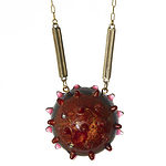 Same piece, different background. Spiky ball flat back resin pendant reminiscent of a spike protein in swirled orange and dark blue resin, set with clear rhinestones. Ball pendant is approximately 1 3/4 inches wide by 1 in deep. Raw brass box chain with gold-tone bar connectors. Designed to go over your head, so no clasp. Photo courtesy of Kathryn Aikin. @lincolnstreetdesign