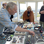 Michael Holmes, the owner of Velvet da Vinci, presented his personal art jewelry collection, which emphasizes political and social issues. Michael is a special resource and friend to AJF, with his wealth of information and knowledge about the contemporary jewelry world, its makers, galleries, and museums. | Mike Holmes handles pieces from his personal collection with onlookers (left to right) Iris Eichenberg, Marion Fulk, Bill Baker, Francine Baker, and Bonnie Levine, photo: Yvonne Montoya