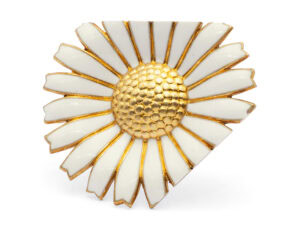 Kim Buck, Chop a Heel and Clip a Toe, 2020, brooch in manipulated Michelsen marguerite brooch, gilded silver with enamel, 1 ¾ inches (44 mm), photo: Dorte Krogh. This piece utilizes the daisy brooch as a ready-made element. The original object has been modified to embody the phrase "Chop a heel and clip a toe," a saying derived from the fairy tale Cinderella, where the stepmother encourages her daughters to cut off part of their feet in order to fit Cinderella's glass slipper.