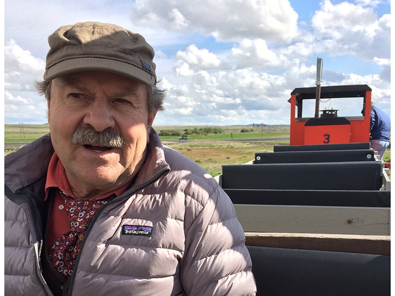 Les riding a small train with cute puffy clouds behind him during a tour at the Inland Northwest Rail Museum, photo courtesy of Autumn Brown