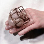“The cage,” explains Finck, “used here as a metaphor for structural constraint, becomes the formative mold within which the delicate glass bodies are blown. Their attempts to expand beyond this framework are integral to their final shape; even once the cage is removed, its imprint remains—visibly and irreversibly shaping their form.” | Caption: Svea Finck, ReFLectME, 2025, ring in glass, copper, model: Jeske Druijts, photo: Saverio Sammartino