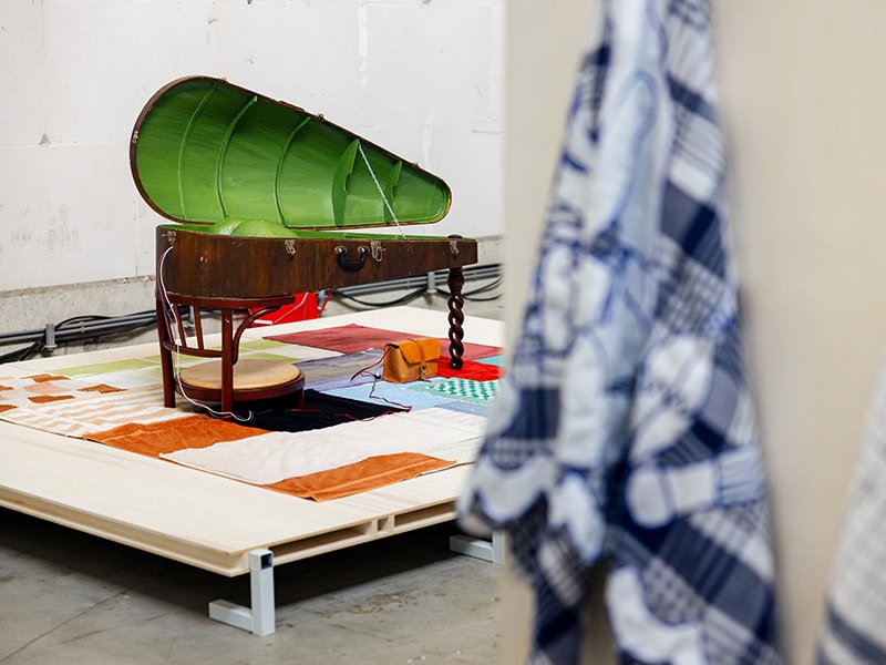 Maaike Fransen, The Servant, 2023, in recycled cello case, reused table leg, wood, fiberglass, polyester, recycled towels, leather, metal, wool, rubber tube, water, on view in The Body Collective’s stand at Dutch Design Week in Eindhoven, Netherlands, October 19–27, 2024, photo: Mitch van Schijndel