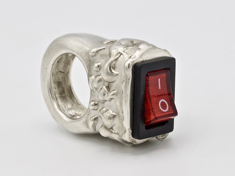 Sara Leme, On and Off, 2024, ring in sterling silver, button, 1 ⅛ x 1 ¾ x ¾ inches (30 x 45 x 20 mm), photo: artist