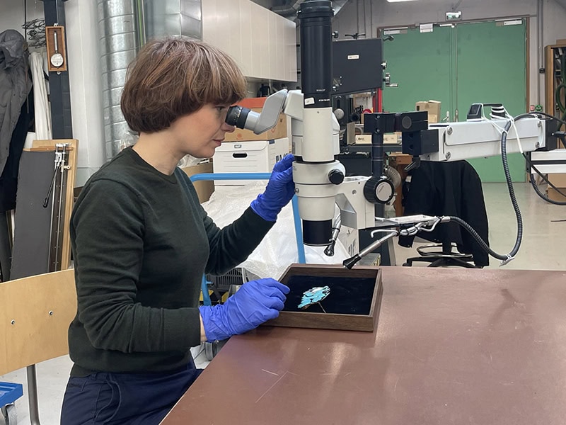 Marion Delarue in the conservation workshops of the Musée des Arts Décoratifs, studying a dian-cui hairpin using a stereomicroscope, photo: © Marion Delarue