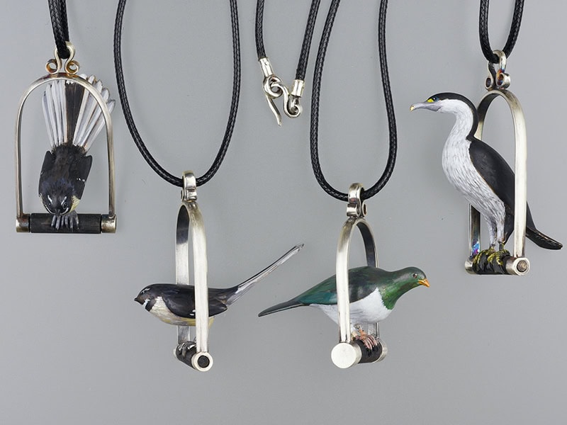 Tania Patterson, Piwakawaka X 2 - Kereru - Pied Shag, 2025, pendants in sterling silver, bronze (bird), enamel paint, nylon cord, 2 ½ x 1 inches (62 x 27 mm) (far right Pied Shag), photo: Michael Couper