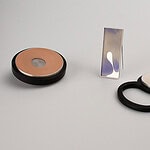 Two brooches and a pendant inspired by worn makeup palettes. | Alice Kupri, Left to Be Forgotten, 2026, (left to right) brooch carved from jet, set with carved ceramics in a silver frame; brooch carved from agate, set in a silver frame; pendant carved from obsidian, set with carved alabaster in a silver frame photo: artist